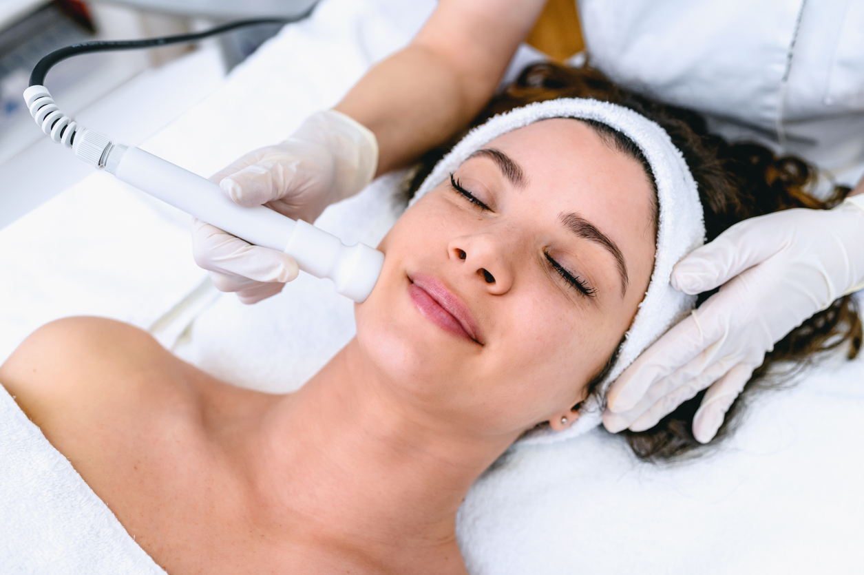 Woman getting ultrasonic and laser face treatment at beauty spa.
